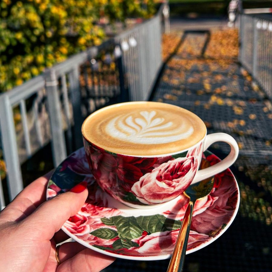 Latte s mliečnym vzorom v kvetinovej šálke na drevenom podnose v Central Caffe v Dubnici nad Váhom